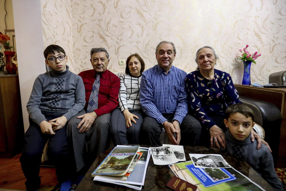 From left: Adil Sharifov's grandson Ramazan Sharifov, uncle Ramiz Humbatov, sister Kamala Sharifova, Adil Sharifov, his mother Adila Ahmadova and grandson Tariyel Sharifov pose for a photo at home in Baku, Azerbaijan, Friday, Nov. 20, 2020. Adil Sharifov, 62, who left his hometown in 1992 during the first war and lives in Azerbaijan's capital, Baku, knows he will find similar devastation if he returns to the city of Jabrayil, which he longs to do. (AP Photo/Aziz Karimov)