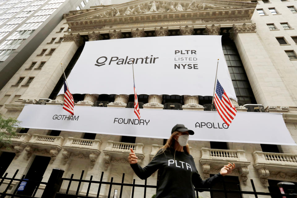 A person poses in front of a banner featuring the logo of Palantir Technologies (PLTR) at the New York Stock Exchange (NYSE) on the day of their initial public offering (IPO) in Manhattan, New York City, U.S., September 30, 2020. REUTERS/Andrew Kelly