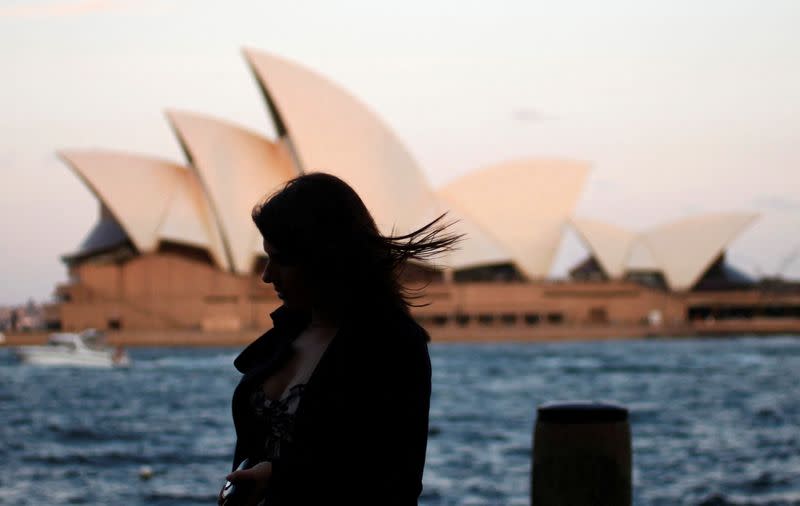 FILE PHOTO: FILE PHOTO: An office worker walks past the Sydney Opera House as she leaves the CBD in Sydney