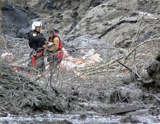 In this photo, published Sunday, March 30, 2014, by the Seattle Times, Randy Fay, a volunteer rescue technician with Snohomish County's SnoHawk 10 rescue helicopter, helps Jetty Dooper, from the Netherlands, after a mudslide struck near Oso, Wash., on Saturday, March 22, 2014. Dooper, while visiting her friend Robin Youngblood who lived in the area, was caught in the slide when a wave of mud crashed into Youngblood's house. (AP Photo/Larry Taylor)