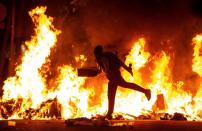 Un manifestante echa al fuego un cartón junto a la Delegación del Gobierno en Barcelona durante los incidentes (EFE/Enric Fontcuberta)