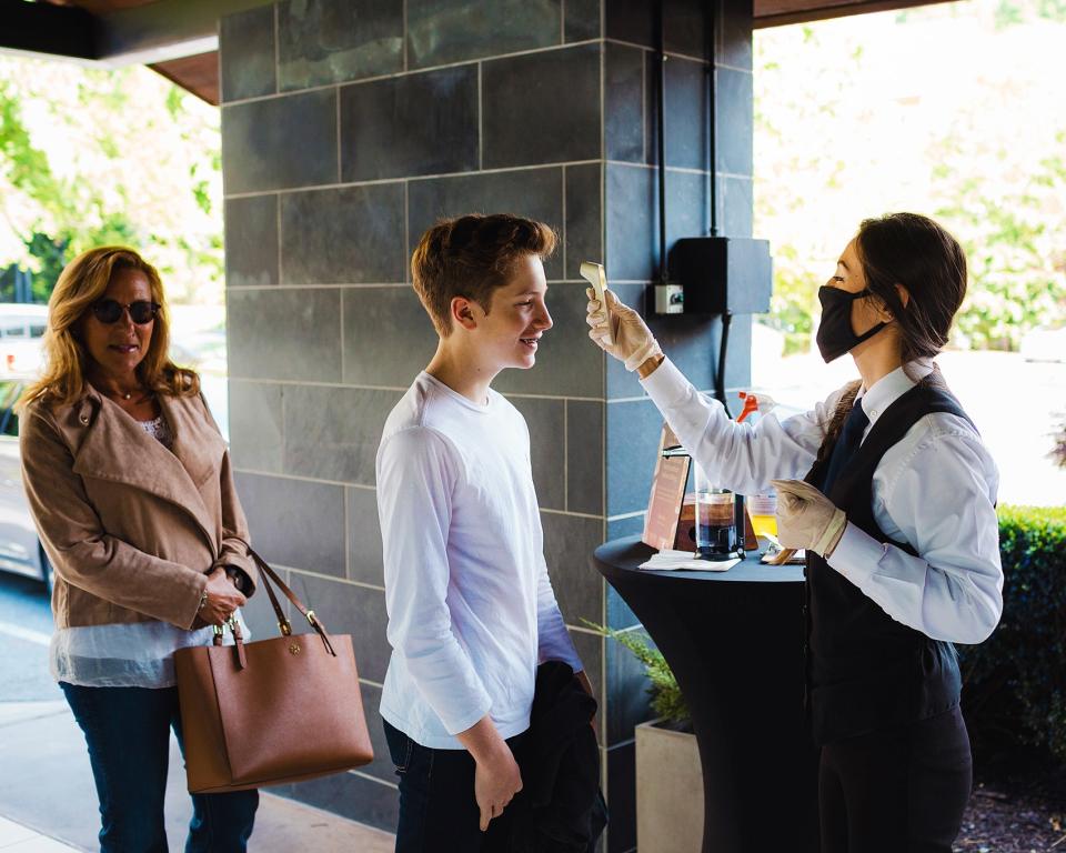 Hostess Nadia Turner takes a customer’s temperature at the entrance to Ray’s On The River.