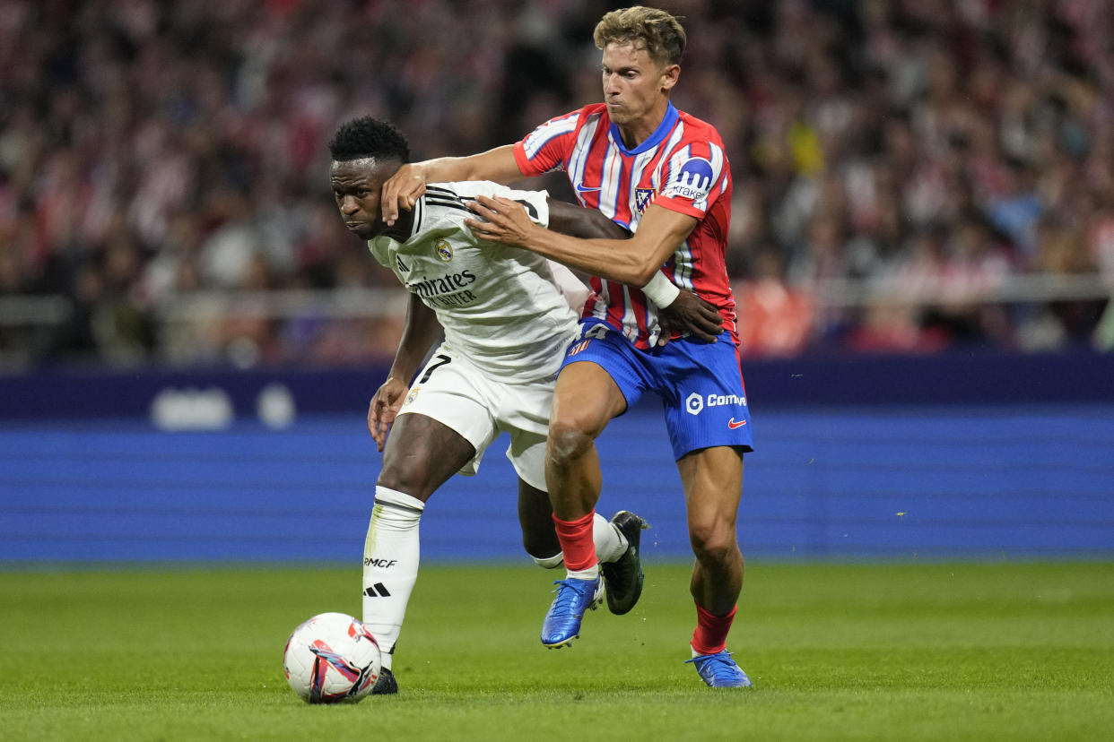 Real Madrid's Vinicius Junior, left, and Atletico Madrid's Marcos Llorente fight for the ball during the La Liga soccer match between Atletico Madrid and Real Madrid at the Metropolitano stadium in Madrid, Spain, Sunday, Sept. 29, 2024. (AP Photo/Bernat Armangue)