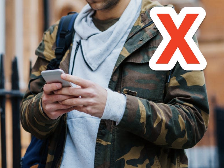 x over man wearing camo-print jacket while texting and walking down a street