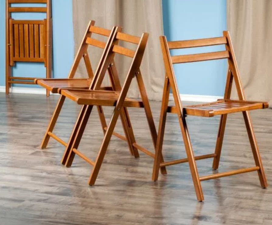 Two wooden chairs facing opposite directions on a hardwood floor with a blue wall behind