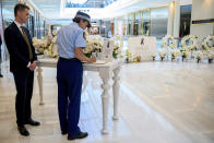 New South Wales Premier Chris Minns, left, watches as the NSW Police Commissioner Karen Webb signs a condolence book while visiting a memorial at Westfield shopping centre at Bondi Junction in Sydney, Thursday, April 18, 2024, after several people were stabbed to death at the shopping centre, Saturday April 13. A Sydney shopping mall has been opened to the public for the first time since it became the scene of a mass stabbing in which six people died, while the Australian prime minister has flagged giving citizenship to an immigrant security guard who was injured while confronting the knife-wielding attacker. (Biance de Marchi/Pool Photo via AP)