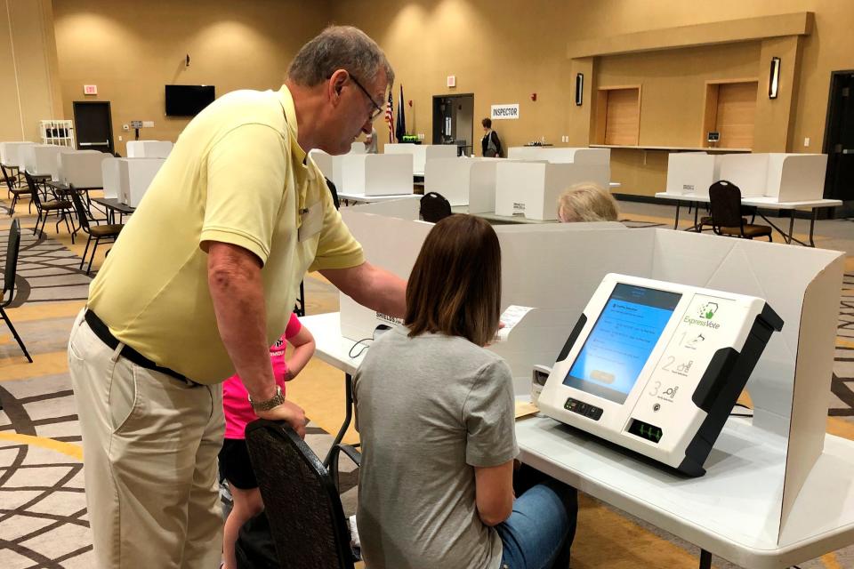 Poll worker David Wyum, left, helps a voter get started on an electronic voting machine at a hotel conference room in West Fargo, N.D., during North Dakota's primary election on Tuesday, June 14, 2022. West Fargo is one of the state's fastest-growing cities with a population of about 37,000 residents.