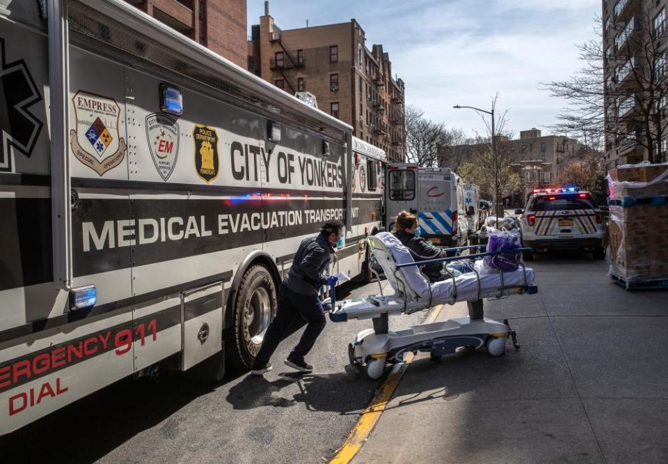 A worker wearing personal protective equipment (PPE), pushes a COVID-19 patient from a specialized bus known as a Medical Evacuation Transport Unit (METU), which carried patients to the Montefiore Medical Center Moses Campus on April 07, 2020 in the Bronx borough of New York City.