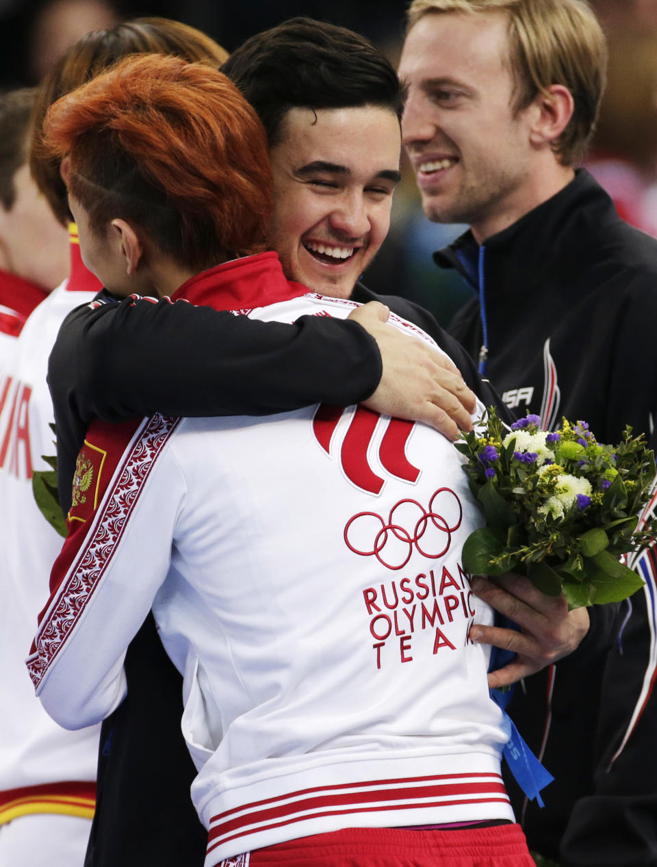 Eduardo Alvarez of the United States, centre, embraces Victor An of Russia during the flower ceremony for the men's 5000m short track speedskating relay final at the Iceberg Skating Palace during the 2014 Winter Olympics, Friday, Feb. 21, 2014, in Sochi, Russia. Russia finished first, followed by the United States and China. (AP Photo/Bernat Armangue)