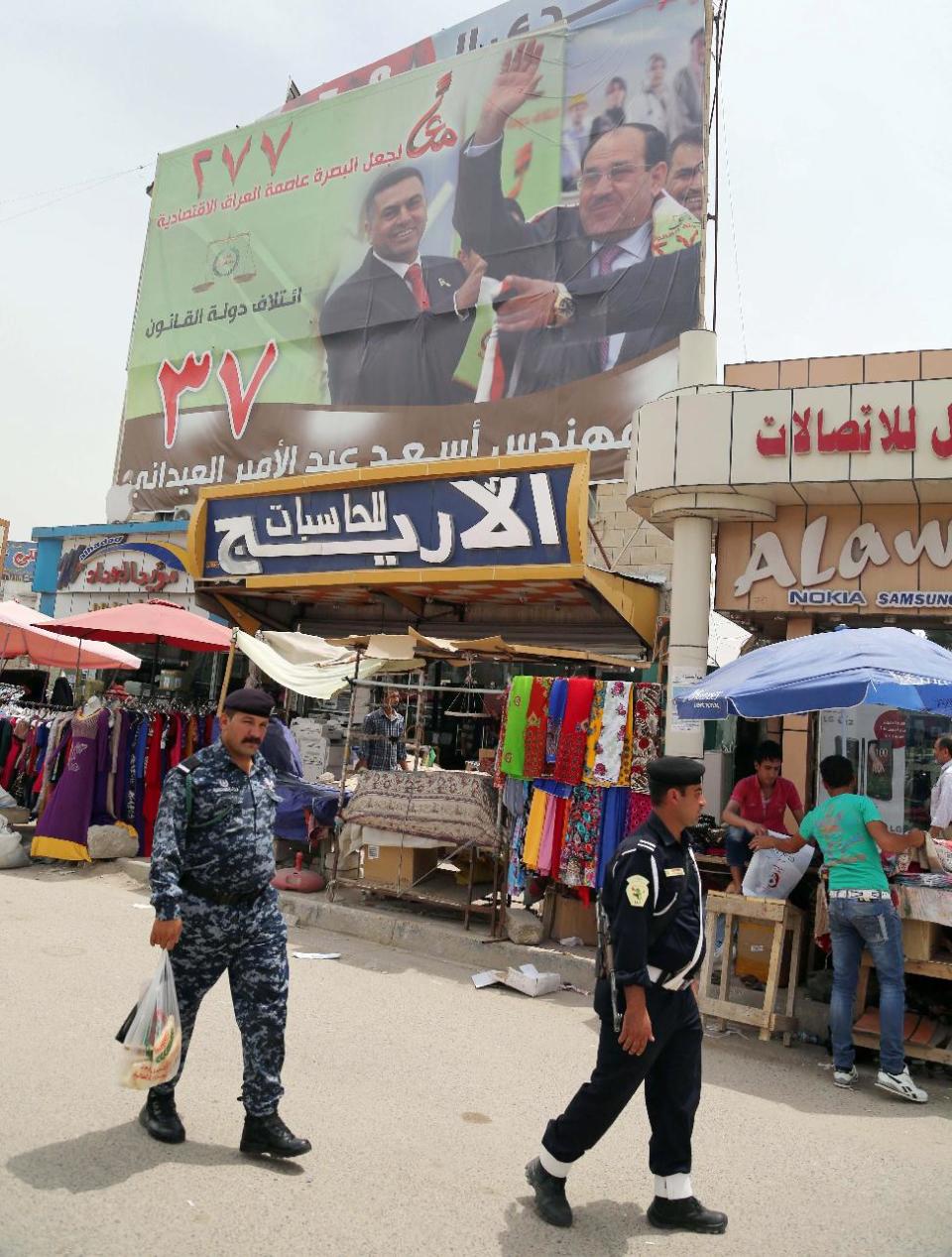 FILE - In this file photo taken on April 27, 2014 security forces pass under a campaign poster of Iraqi Prime Minister Nouri al-Maliki in Basra, Iraq's second-largest city, 340 miles (550 kilometers) southeast of Baghdad, Iraq. If Iraqi Prime Minister Nouri al-Maliki wins a third four-year term in parliamentary elections Wednesday, he is likely to rely on a narrow sectarian Shiite base, only fueling divisions as Iraq slides deeper into bloody Shiite-Sunni hatreds. (AP Photo/ Nabil al-Jurani, File)