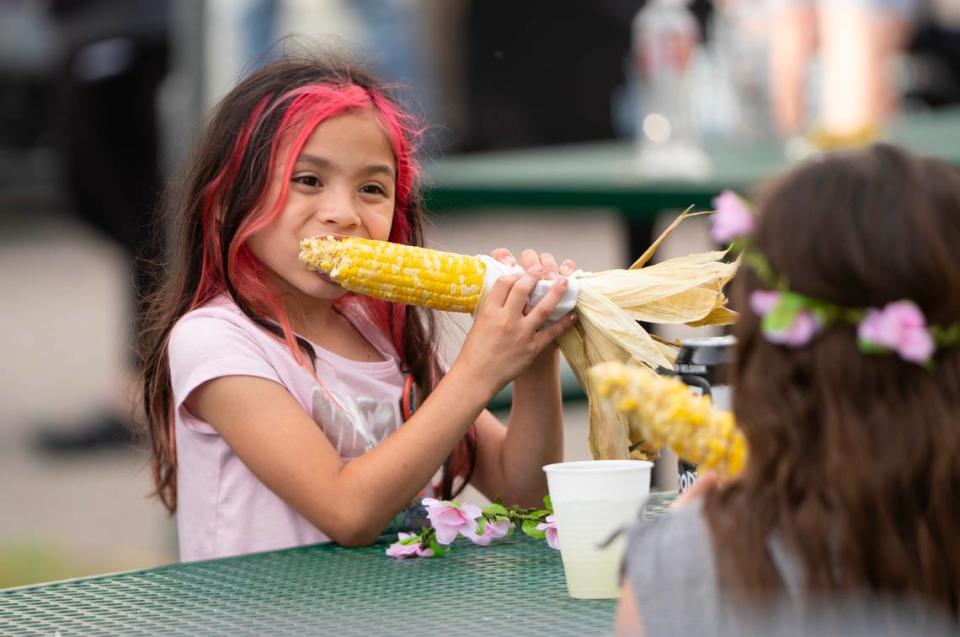 A girl gets her teeth into roasted corn at the Wichita Riverfest’s food court.