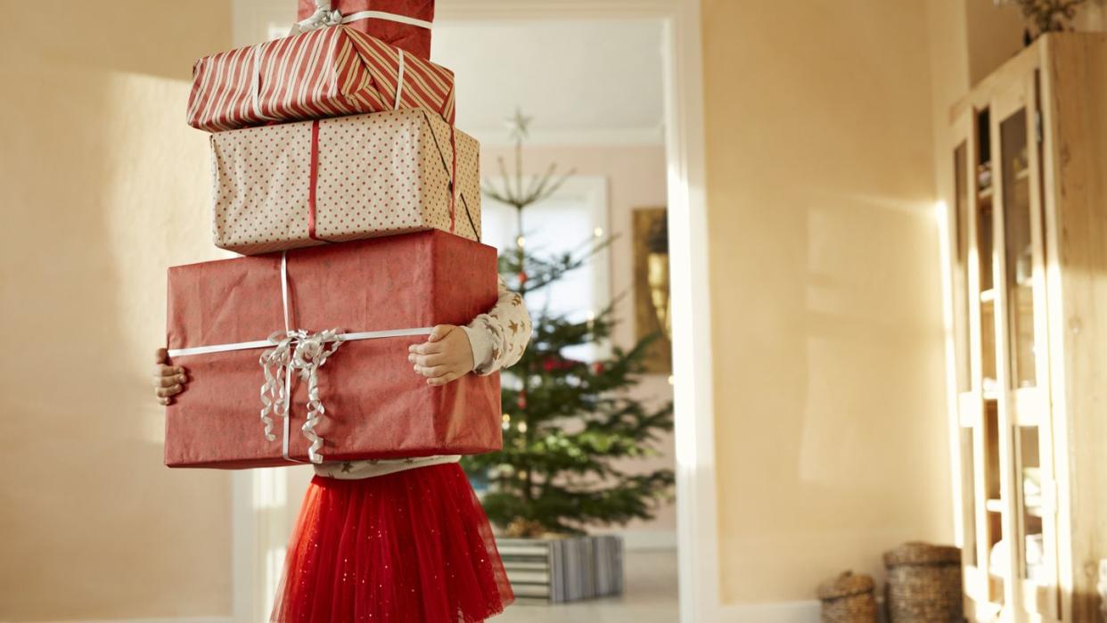 girl holding tall stack of christmas presents