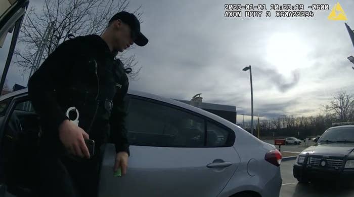 A man in a uniform and cap stands by a car