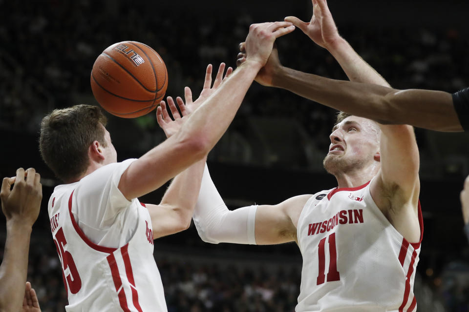 Wisconsin forwards Nate Reuvers (35) and Micah Potter (11) reach for a rebound during the first half of an NCAA college basketball game against Michigan State, Friday, Jan. 17, 2020, in East Lansing, Mich. (AP Photo/Carlos Osorio)