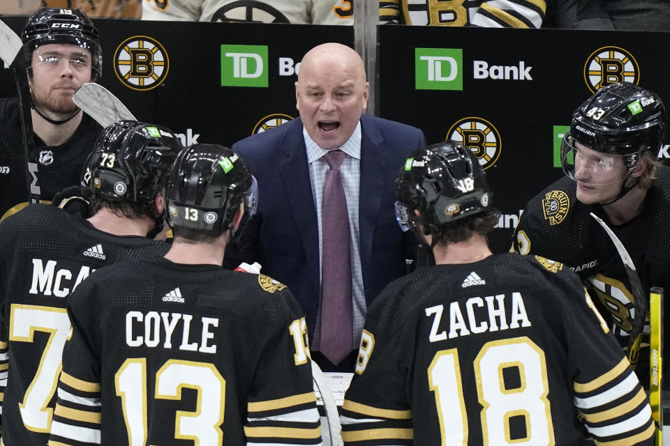 Boston Bruins head coach Jim Montgomery, center, speaks with members of the team in the third period of an NHL hockey game against the Pittsburgh Penguins, Thursday, Jan. 4, 2024, in Boston. (AP Photo/Steven Senne)