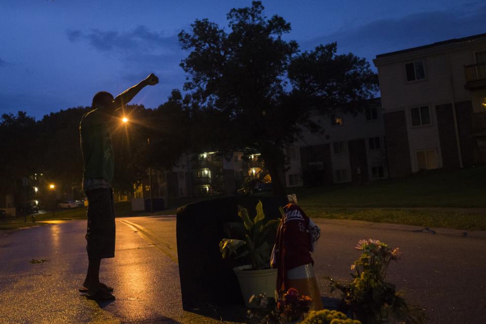 A local resident stands with his arm up over a makeshift memorial at the site where unarmed teen Michael Brown was shot dead in Ferguson, Missouri August 27, 2014. Authorities on Wednesday disbanded what had been a command center in Ferguson, Missouri, for law enforcement responding to sometimes violent protests over the killing of an unarmed black teenager by a white police officer. Officers loaded up the remaining fire trucks and police vans that were part of the temporary law enforcement headquarters in a strip mall parking lot, rolling out after several days of subdued demonstrations. REUTERS/Adrees Latif (UNITED STATES - Tags: CRIME LAW CIVIL UNREST)