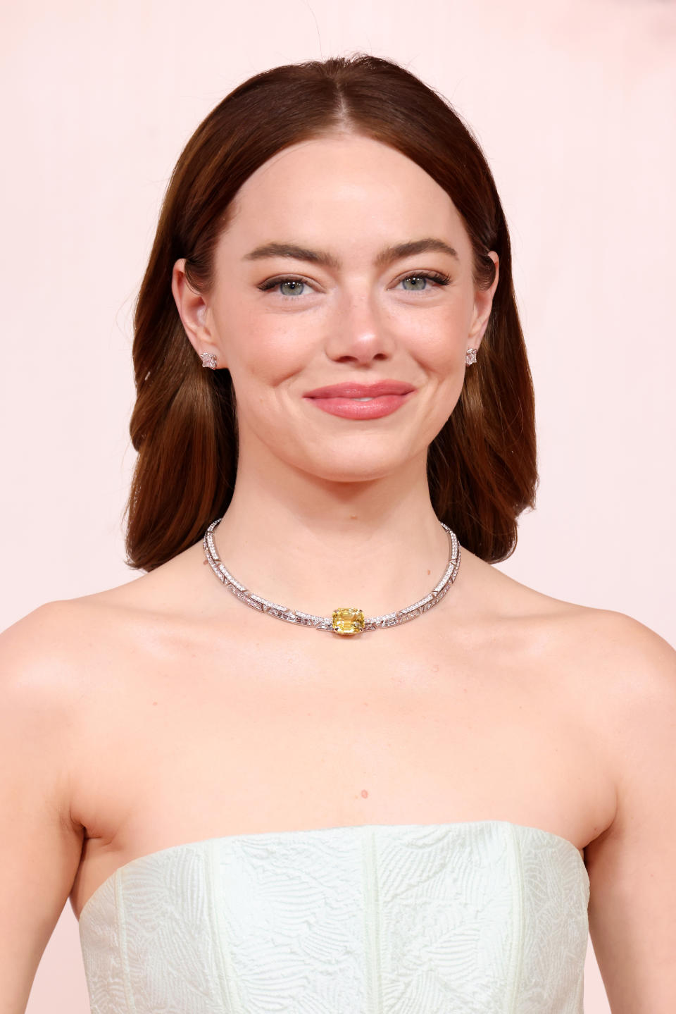 A closeup of Emma Stone on the red carpet, wearing a strapless dress and a statement necklace