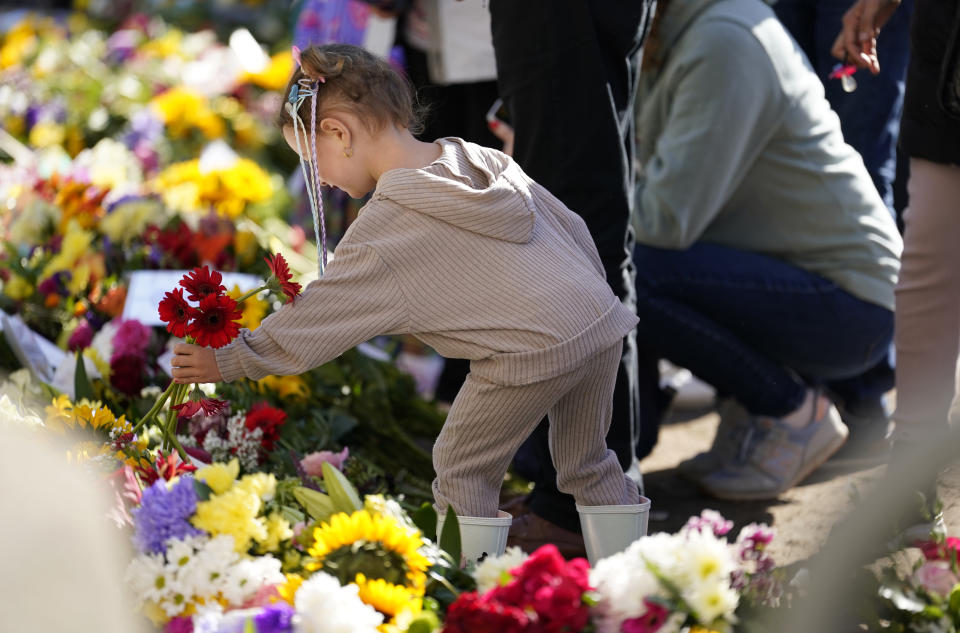 A child lays flowers outside Cambridge Gate on the Long Walk in Windsor ahead of the funeral of Queen Elizabeth II on Monday