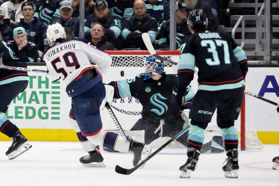 Columbus Blue Jackets right wing Yegor Chinakhov (59) sends the puck past Seattle Kraken goaltender Joey Daccord, center right, during the third period of an NHL hockey game, Sunday, Jan. 28, 2024, in Seattle. (AP Photo/John Froschauer)