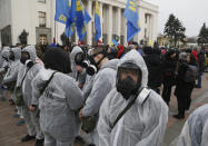 Protesters in protective suits and masks take part in a rally in front of the parliament building in Kyiv, Ukraine, Tuesday, March 17, 2020. Protesters demanded lawmakers to stop working amid nation-wide quarantine in order to prevent hastily adopting unpopular laws. In an additional set of measures preventing the spread of the new coronarivus, Ukrainian authorities ruled to close public places except food markets, pharmacies and gas stations starting from Tuesday in Kyiv and other regions, and restrict the use of public transport from Kyiv to other Ukrainian cities. For most people, the new coronavirus causes only mild or moderate symptoms. For some it can cause more severe illness, especially in older adults and people with existing health problems. (AP Photo/Efrem Lukatsky)
