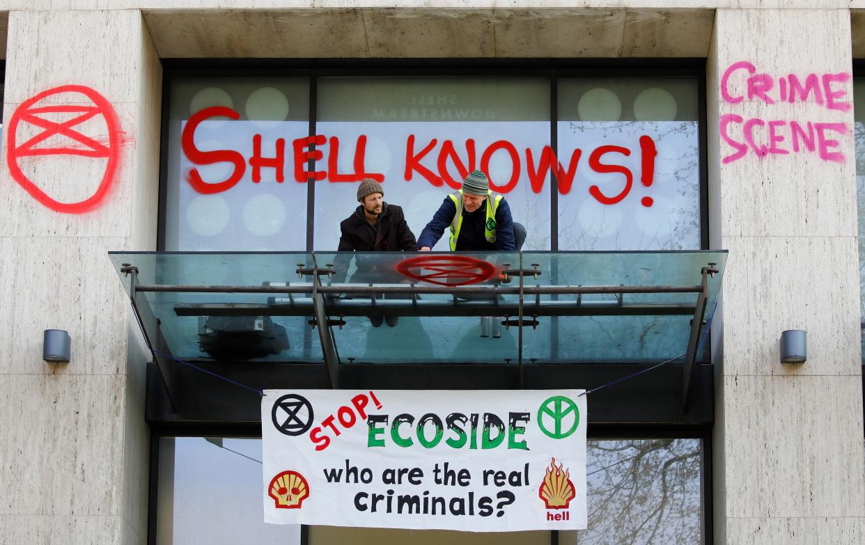 A climate activist sprays graffiti on the entrance to the Shell's British offices. (Photo: TOLGA AKMEN via Getty Images)