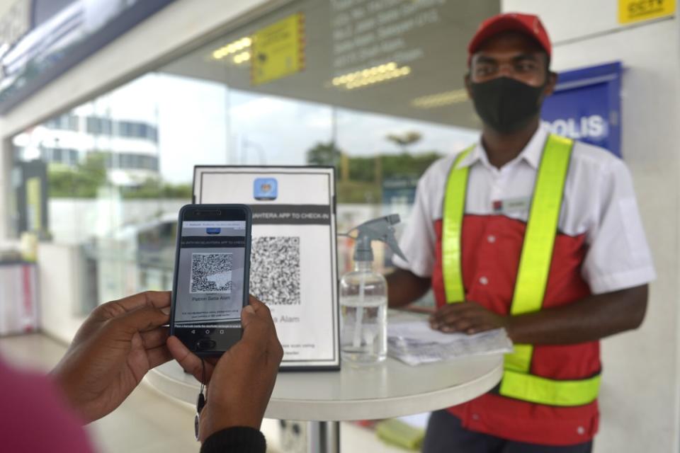 A customer checks-in using the MySejahtera app before entering a petrol station in Setia Alam November 10, 2020. ― Picture by Miera Zulyana