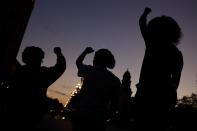 FILE - In this June 23, 2020, file photo, people raise their fists in Kansas City, Mo., during a protest over the death of Black people at the hands of police. (AP Photo/Charlie Riedel, File)