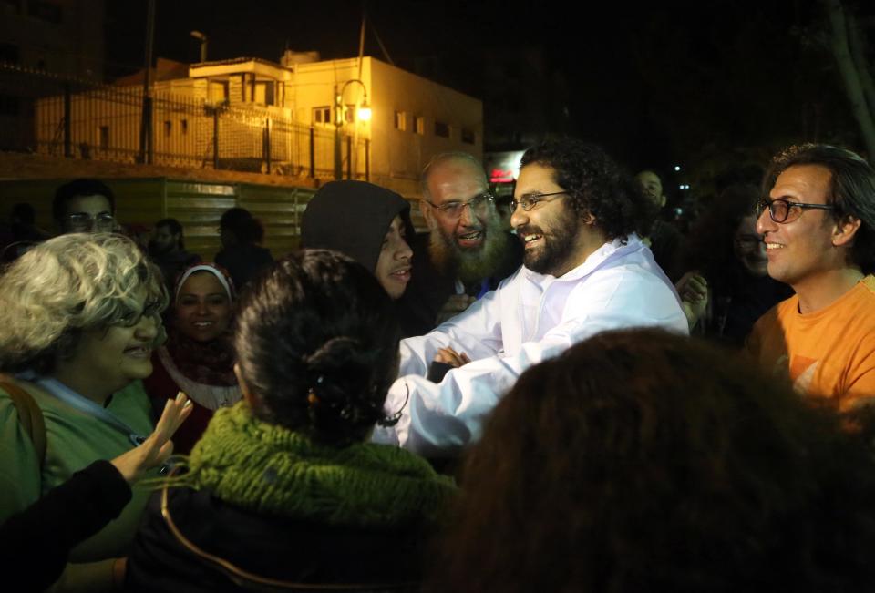 Alaa Abdel-Fattah, center in white, a prominent activist and a leading figure in the 2011 uprising against Egyptian autocrat Hosni Mubarak, is welcomed after he was released from the main central security office in Cairo, Egypt, Sunday, March 23, 2014. Abdel-Fattah was arrested from his home on Nov. 28, 2013, and he and his wife accuse police of attacking them during the arrest. Egyptian court on Sunday ordered the release on bail pending trial of Abdel-Fattah charged with breaking a new law that heavily restricts protests, after he spent nearly four months in jail. (AP Photo/Roger Anis, El Shorouk Newspaper) EGYPT OUT