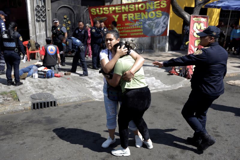 A woman is comforted by a friend after a relative was gunned down by unknown assailants outside a garage, in Mexico City