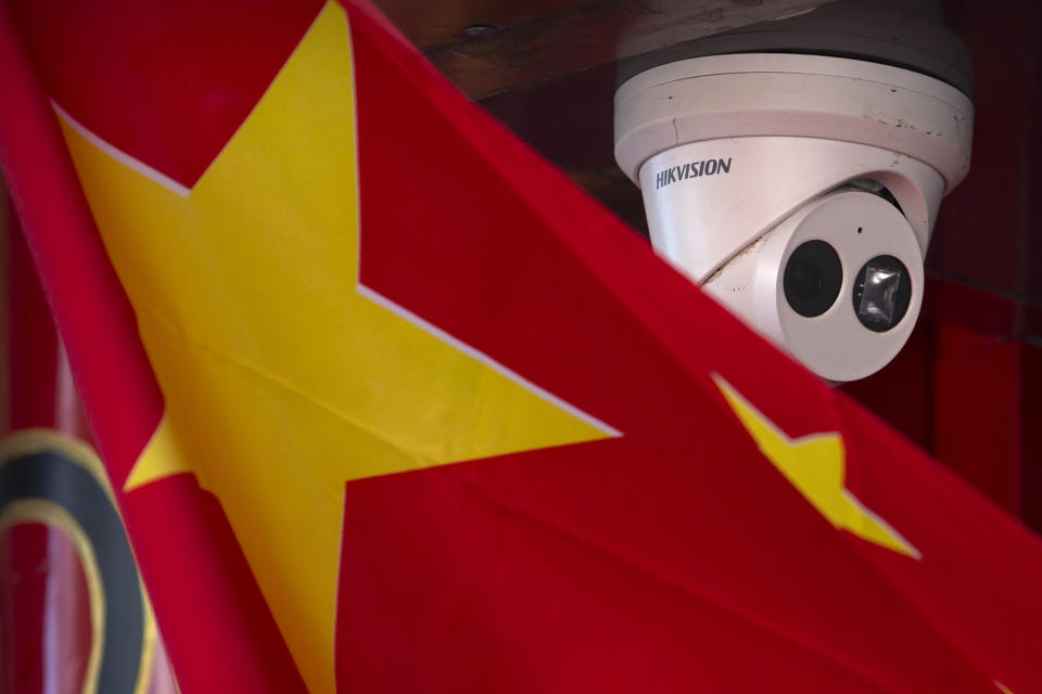 FILE - A Chinese flag hangs near a security camera outside of a shop in Beijing on Oct. 8, 2019. China has long been seen by the U.S. as a prolific source of anti-American propaganda but less aggressive in its influence operations than Russia, which has used cyberattacks and covert operations to disrupt U.S. elections and denigrate rivals. But many in Washington now think China is increasingly adopting tactics associated with Russia — and there's growing concern the U.S. isn't doing enough to respond. (AP Photo/Mark Schiefelbein, File)