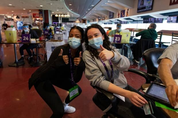 Volunteers give the thumbs-up during a temporary COVID-19 vaccine clinic at the Woodbine racetrack and casino, in northeast Toronto, on May 5, 2021. (Evan Mitsui/CBC - image credit)