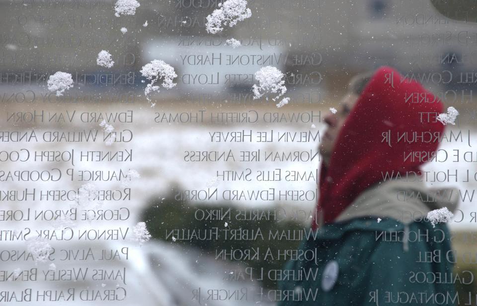 Mary Bruno looks at some of the snow-covered names of Colorado men and women killed in conflict since Colorado became a state, inscribed on the Colorado Freedom Memorial located in Aurora