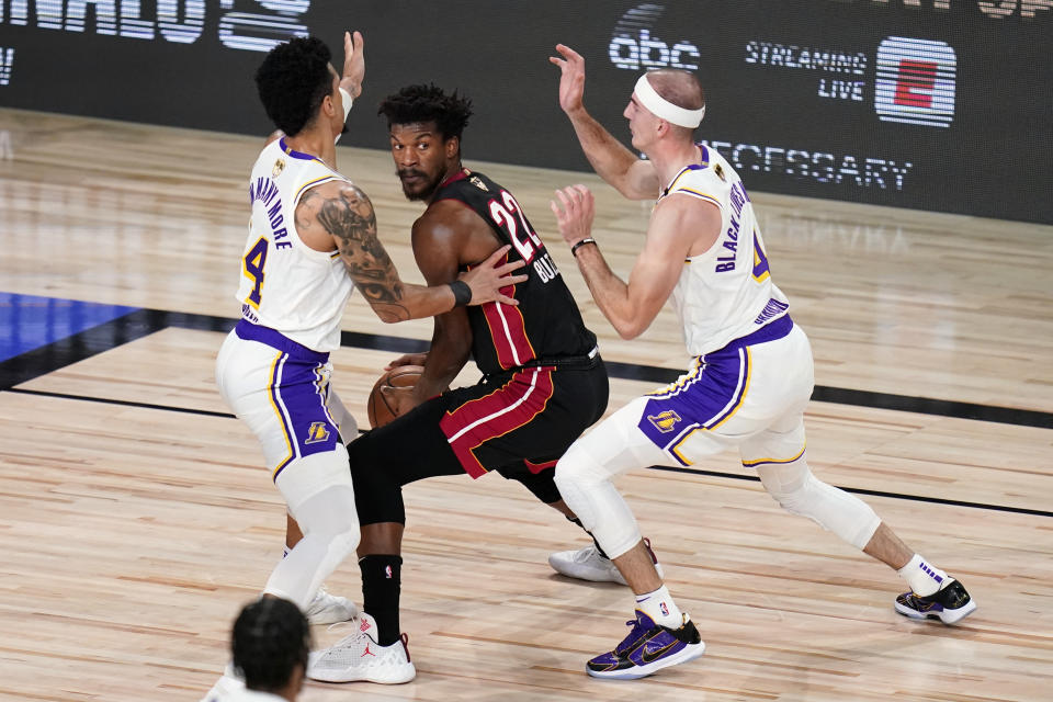 Miami Heat's Jimmy Butler (22) looks to pass against Los Angeles Lakers' Danny Green (14) and Alex Caruso (4) during the first half in Game 6 of basketball's NBA Finals Sunday, Oct. 11, 2020, in Lake Buena Vista, Fla. (AP Photo/John Raoux)