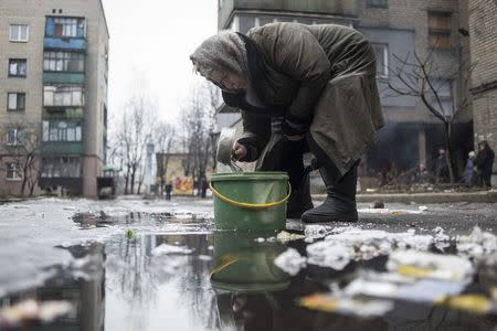 An elderly woman collects water from a puddle in Debaltseve, February 3, 2015. REUTERS/Sergey Polezhaka