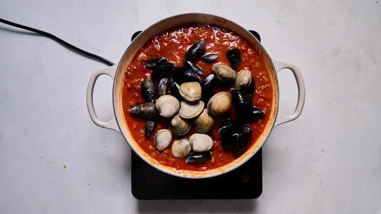 mussels and clams closed in pot of tomato broth