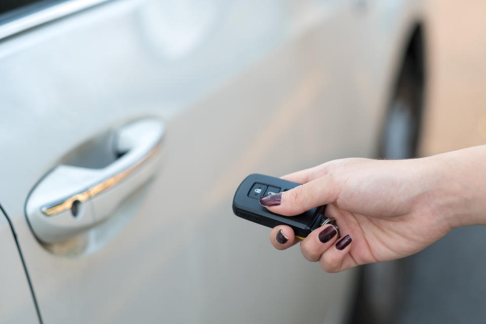 Person using a car key remote to unlock a vehicle