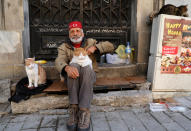 <p>A man sits with cats on a street on Jan. 7, 2018. (Photo: Goran Tomasevic/Reuters) </p>