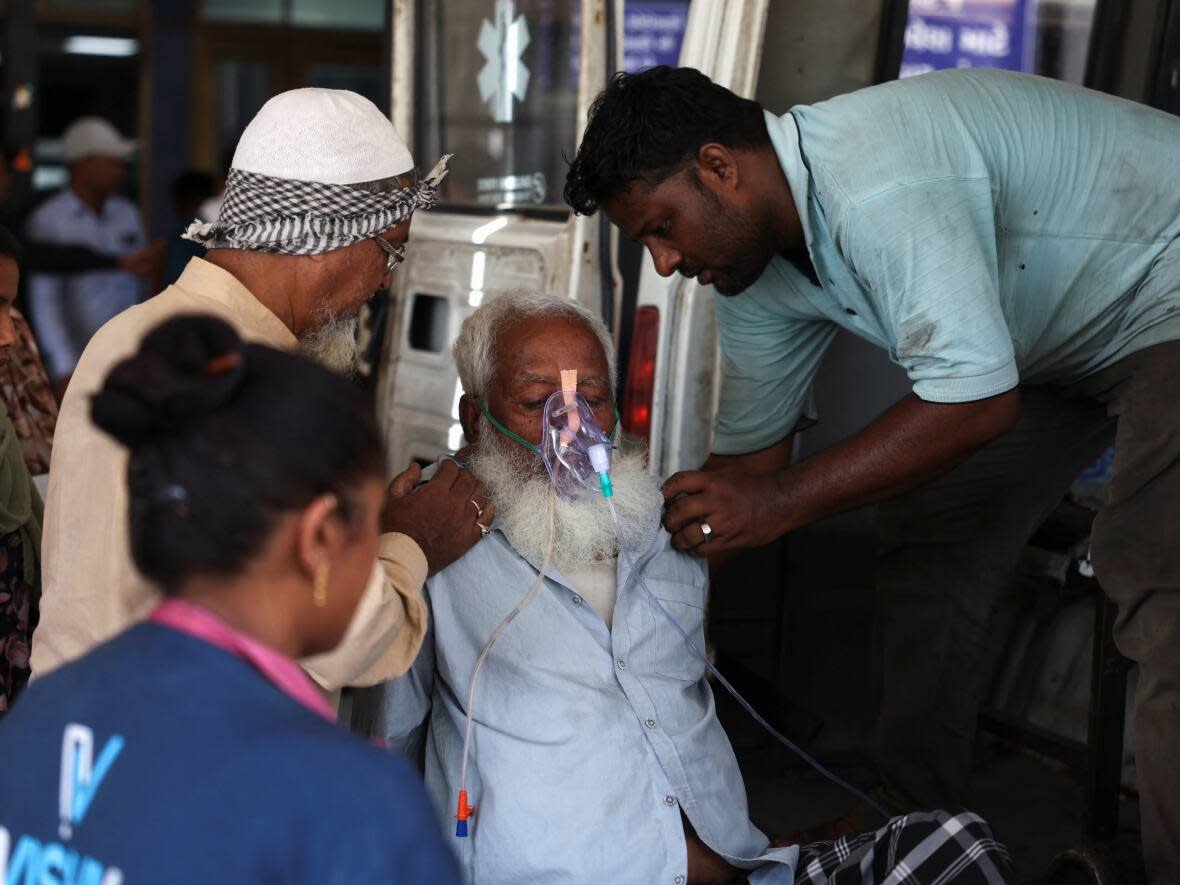 An elderly man, who medical officials said was suffering from heat exhaustion, was helped into a hospital for treatment during a heat wave in Ahmedabad, India, on May 24. The country has been dealing with a heat wave for more than a week. (Amit Dave/Reuters - image credit)