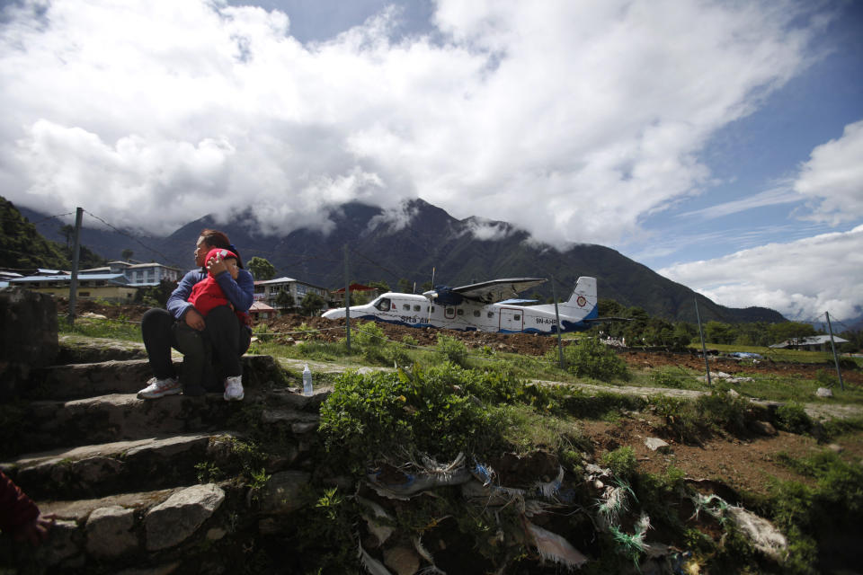 In this Sunday, May 26, 2013 photo, a woman takes a rest with her son near Lukla airport, Nepal. Carved out of side of a mountain, the airport was built by Sir Edmund Hillary in 1965, and at an altitude of 2,843 meters (9,325 feet) it has earned the reputation of being one of the most extreme and dangerous airports in the world. (AP Photo/Niranjan Shrestha)