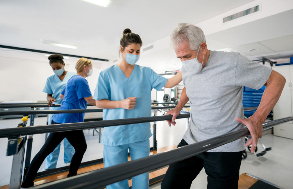 Group of doctors and patients in a rehab center wearing facemasks while doing their physiotherapy - COVID-19 pandemic lifestyle concepts