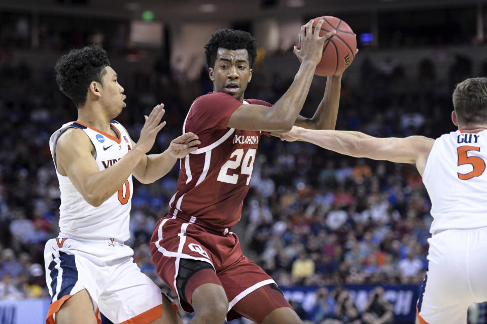 Oklahoma guard Jamal Bieniemy (24) is defended by Virginia guard Kihei Clark (0) and Kyle Guy (5) during the first half of a second-round game in the NCAA men's college basketball tournament Sunday, March 24, 2019, in Columbia, S.C. (AP Photo/Sean Rayford)