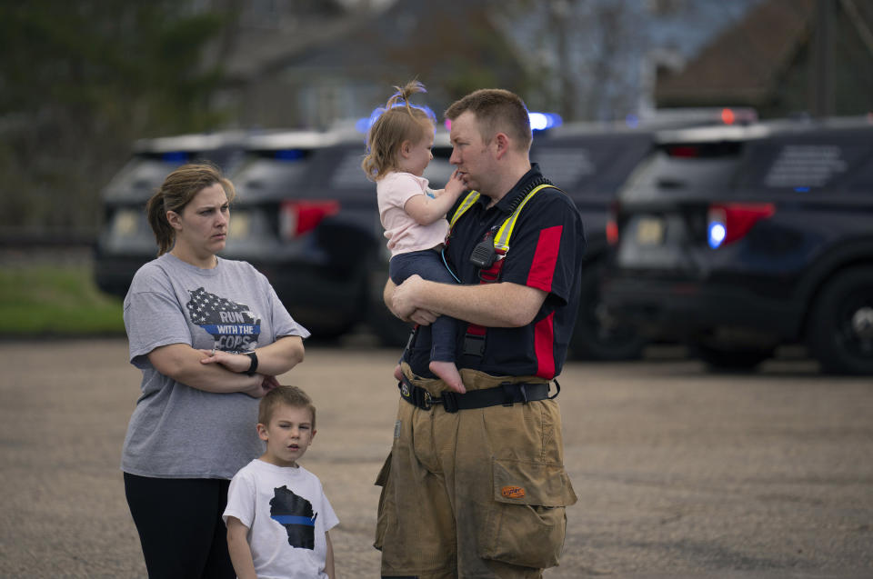 A firefighter stands with his family across the street from the Baldwin, Wis., funeral home where St. Croix County Deputy Kaitie Leising's body arrived Sunday afternoon, May 7, 2023. Leising was shot and killed during a traffic stop Saturday. (Jeff Wheeler/Star Tribune via AP)