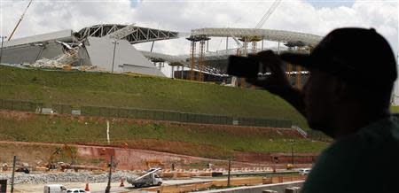 A man takes a picture of a crane that collapsed on the site of the Arena Sao Paulo stadium, known as "Itaquerao", which will host the opening soccer match of the 2014 World Cup, in Sao Paulo November 27, 2013. REUTERS/Nacho Doce