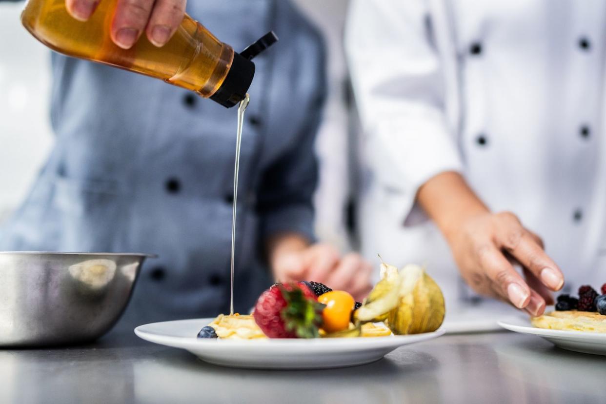 close up pf a chef pouring honey on waffle at commercial kitchen