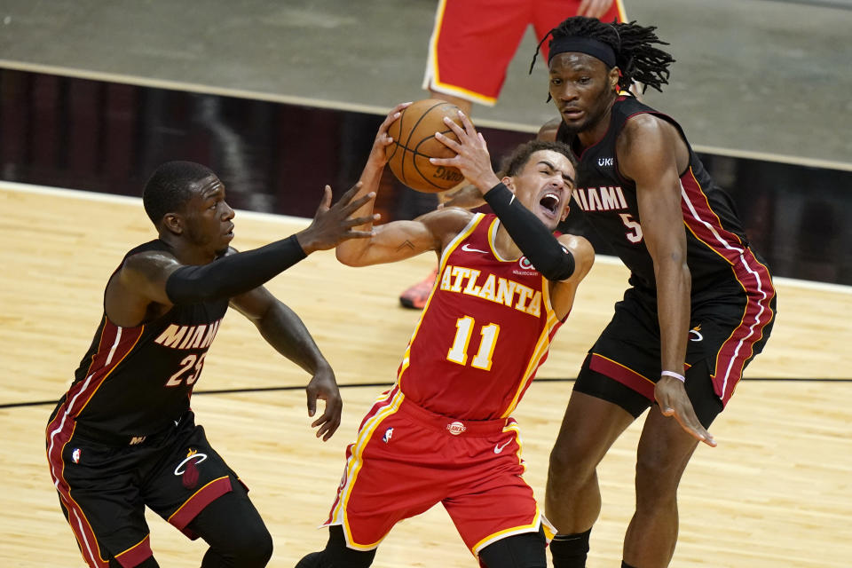 Atlanta Hawks guard Trae Young (11) drives to the basket as Miami Heat guard Kendrick Nunn (25) and forward Precious Achiuwa (5) defend during the first half of an NBA basketball game, Sunday, Feb. 28, 2021, in Miami. (AP Photo/Lynne Sladky)