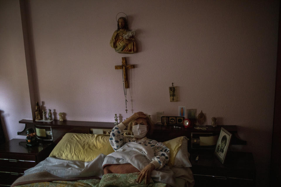 Maria Perez Gomez, 70, reacts to medical workers arriving at her home in Barcelona, Spain, April 1, 2020. She reluctantly called them after suffering breathing problems, a cough and a fever. "Please leave me here at home, don't take me to the hospital," she begged the doctor. "Tell me, doctor, that I don't have the virus." (AP Photo/Emilio Morenatti)