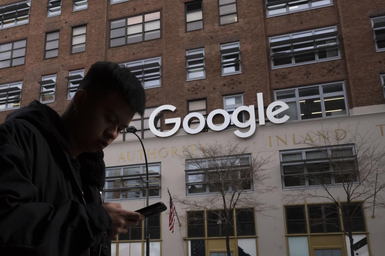 In this Dec. 17, 2018 photo a man using a mobile phone walks past Google offices in New York.