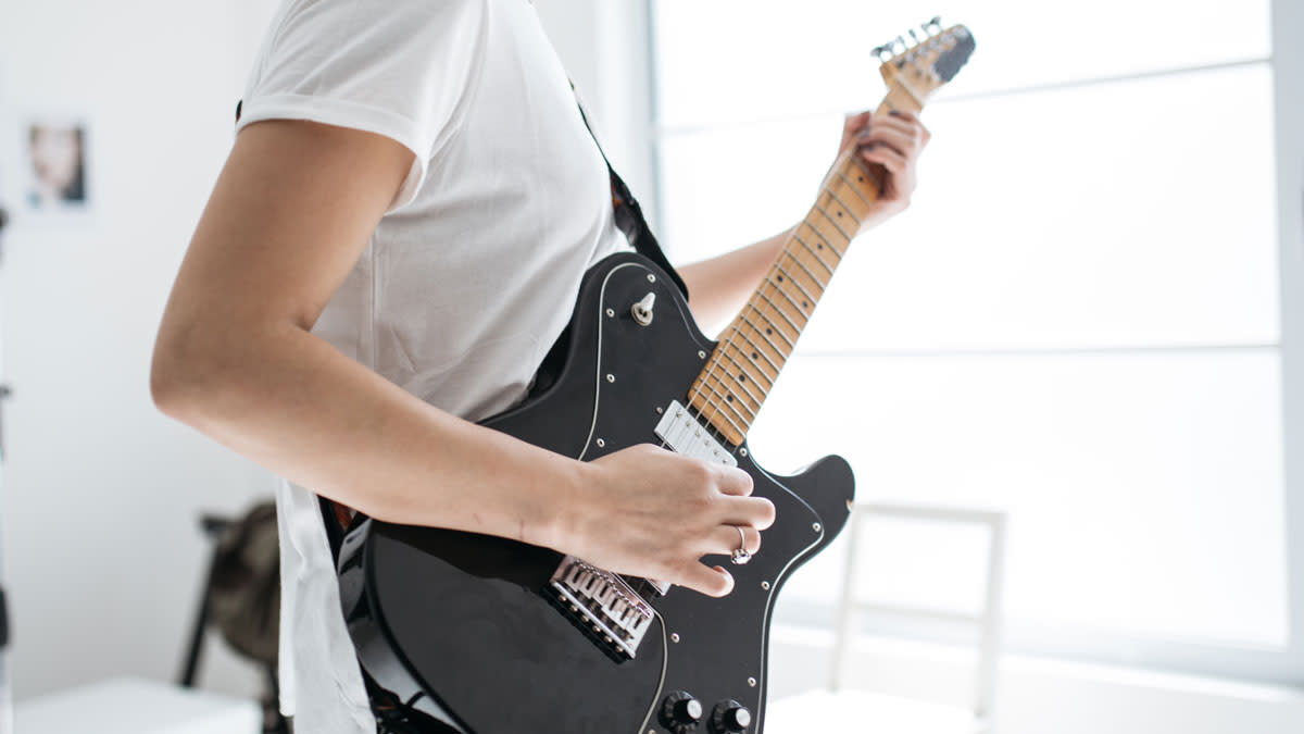  Young woman playing electric guitar. 