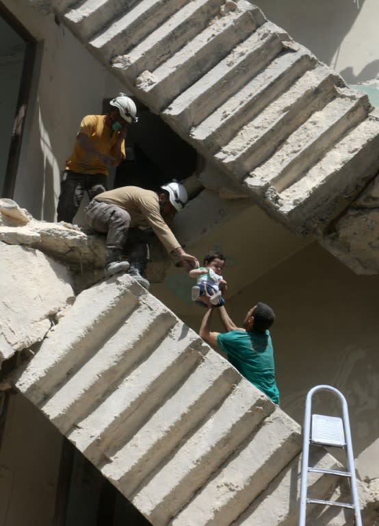 Syrian civil defence volunteers evacuate a baby from a destroyed building following a reported air strike on the rebel-held neighbourhood of al-Kalasa in Aleppo, on April 28, 2016