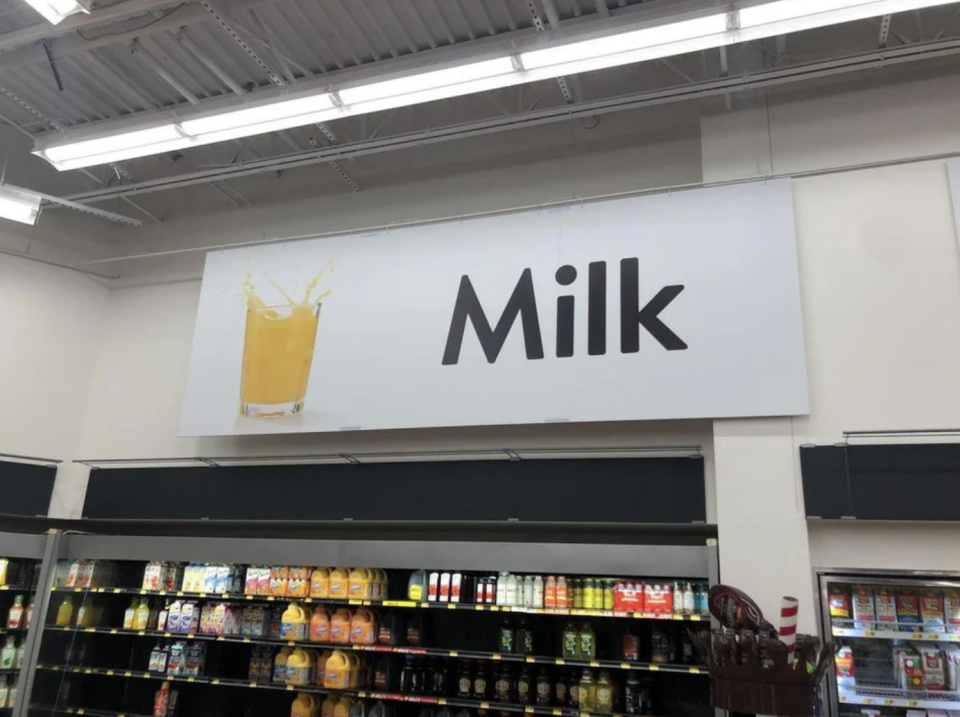 A sign with orange juice that says "Milk"